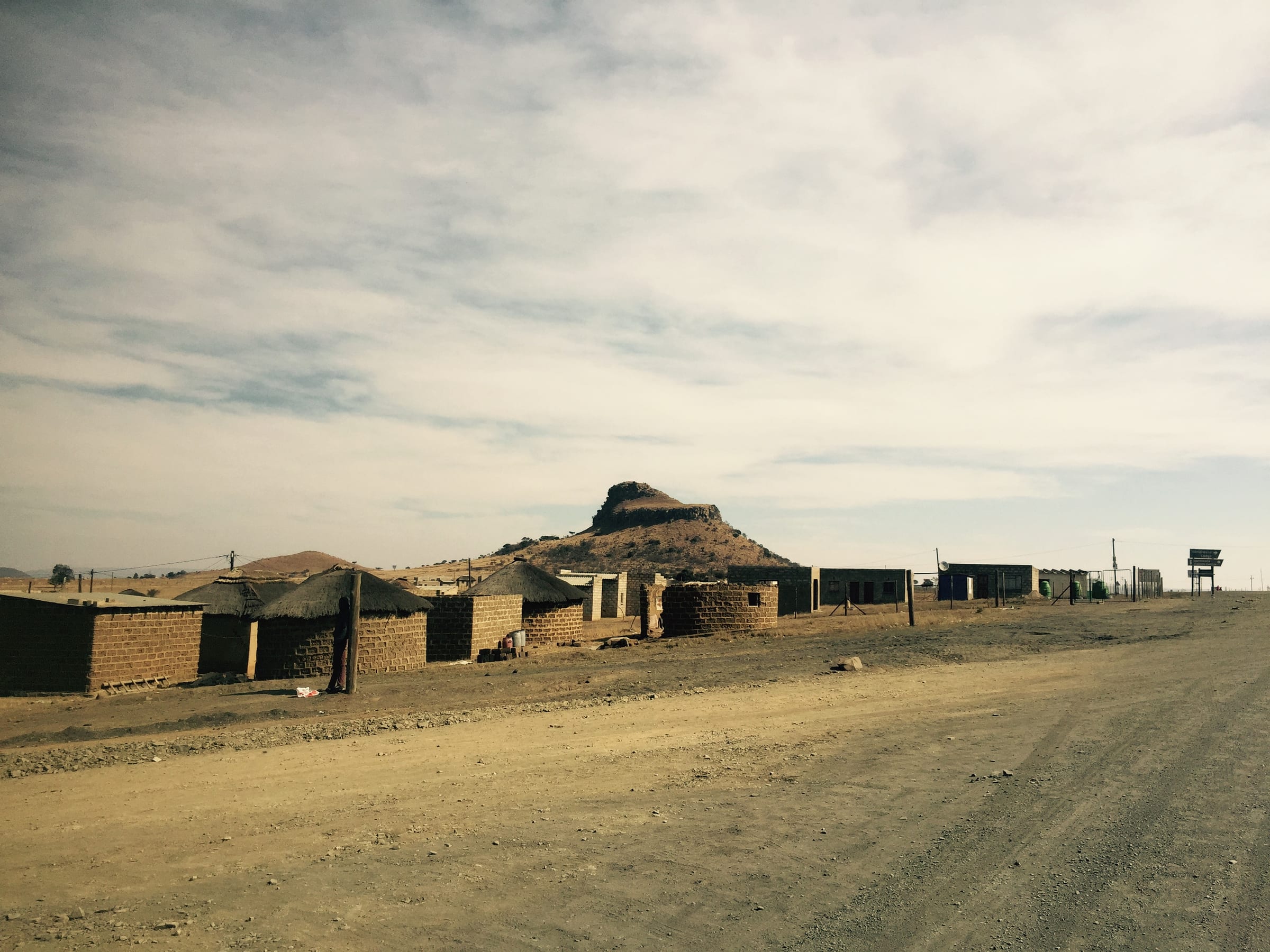 Scattered rural dwellings across rolling dry hills, the land stretching to a low horizon.
