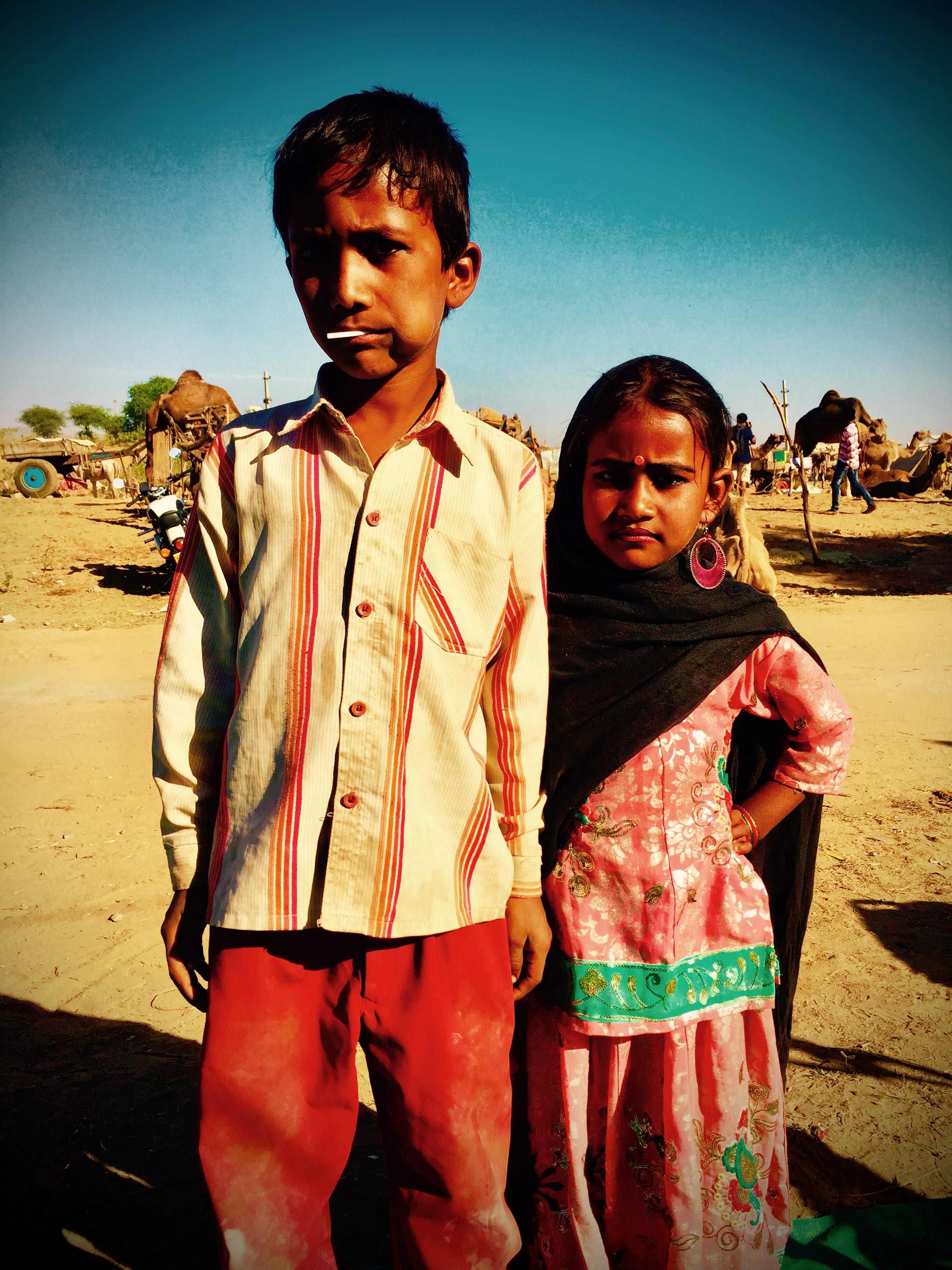 Two children stand together before a distant desert fort.