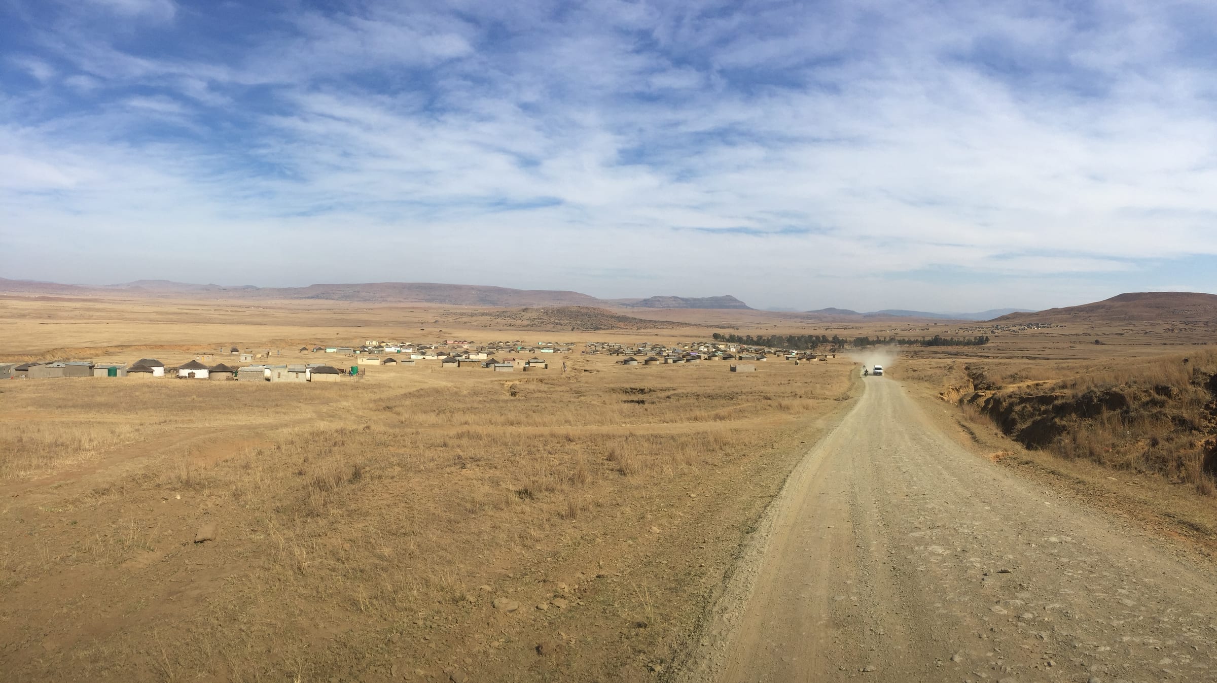 A dirt road running straight into a vast open plain beneath an enormous sky.