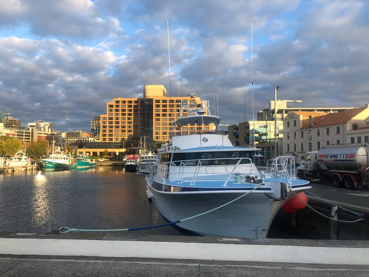 Boats moored along a working waterfront backed by warehouses and apartments.