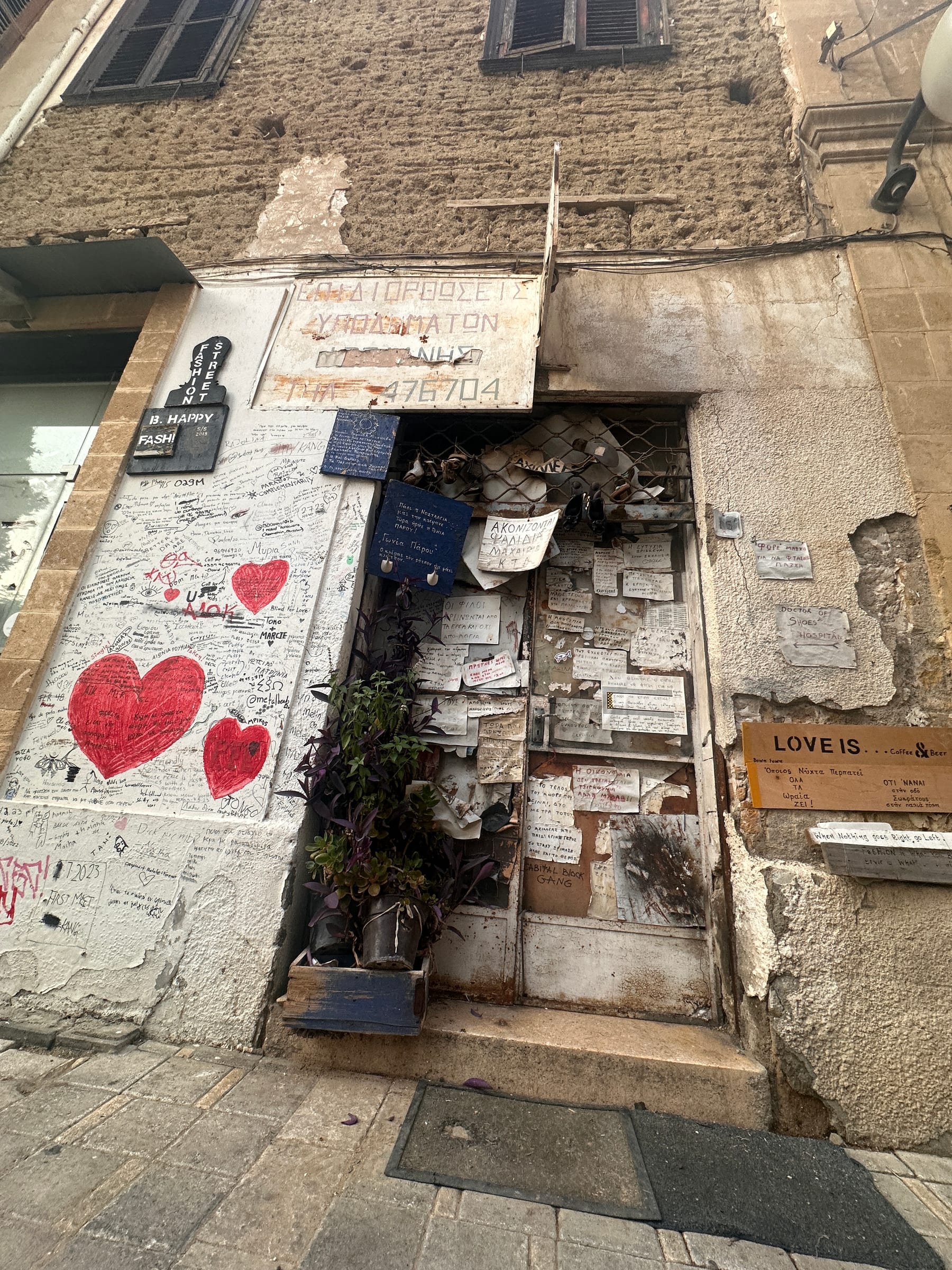 A weathered shopfront and wall seen from above, a large painted red heart on the stonework.