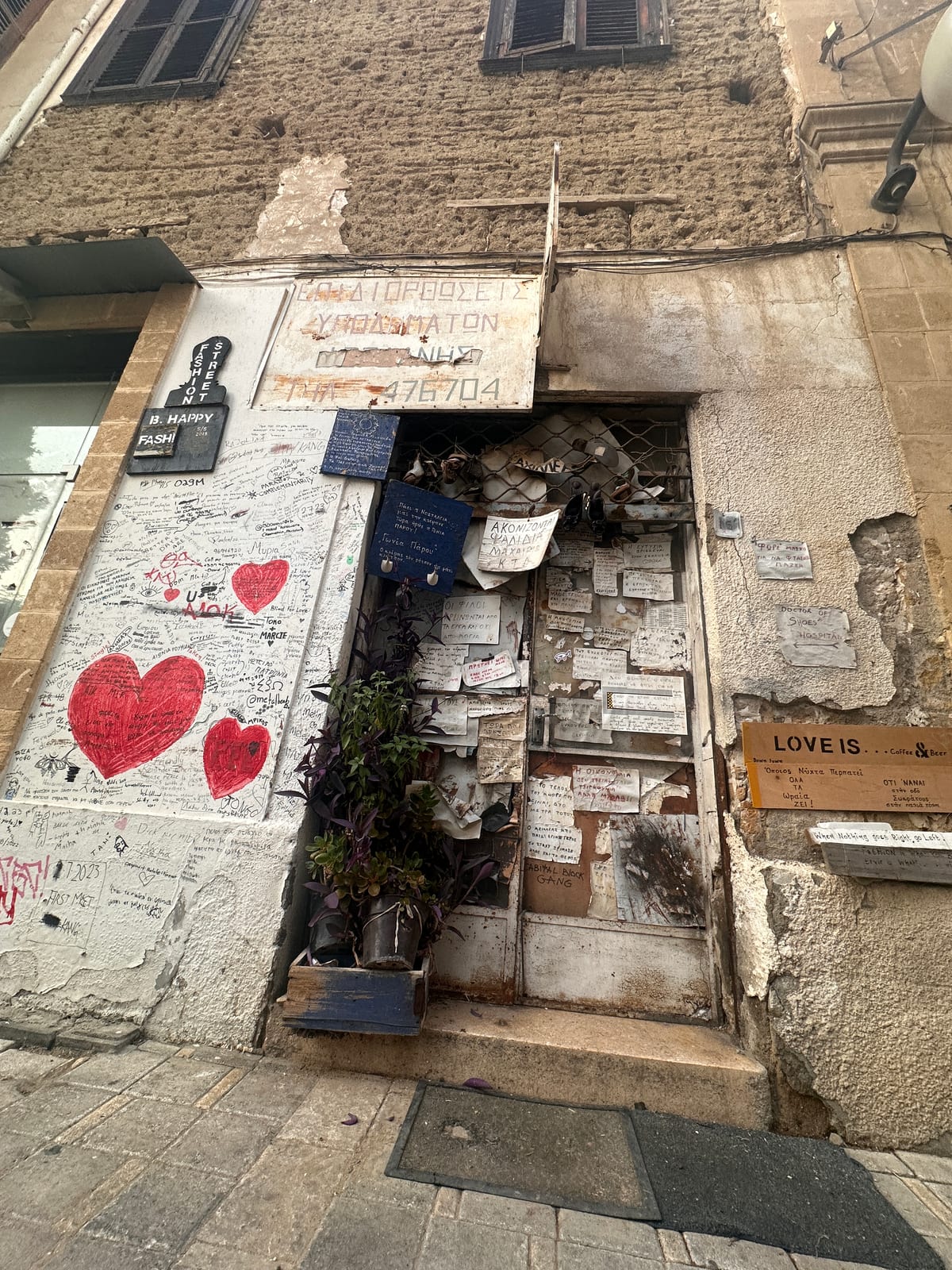 A weathered shopfront and wall seen from above, a large painted red heart on the stonework.