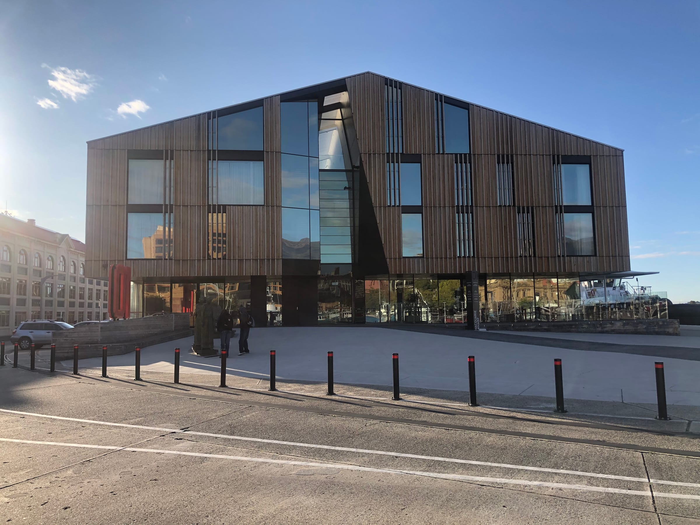 A dark timber-clad modern building with angular windows seen against a clear sky.