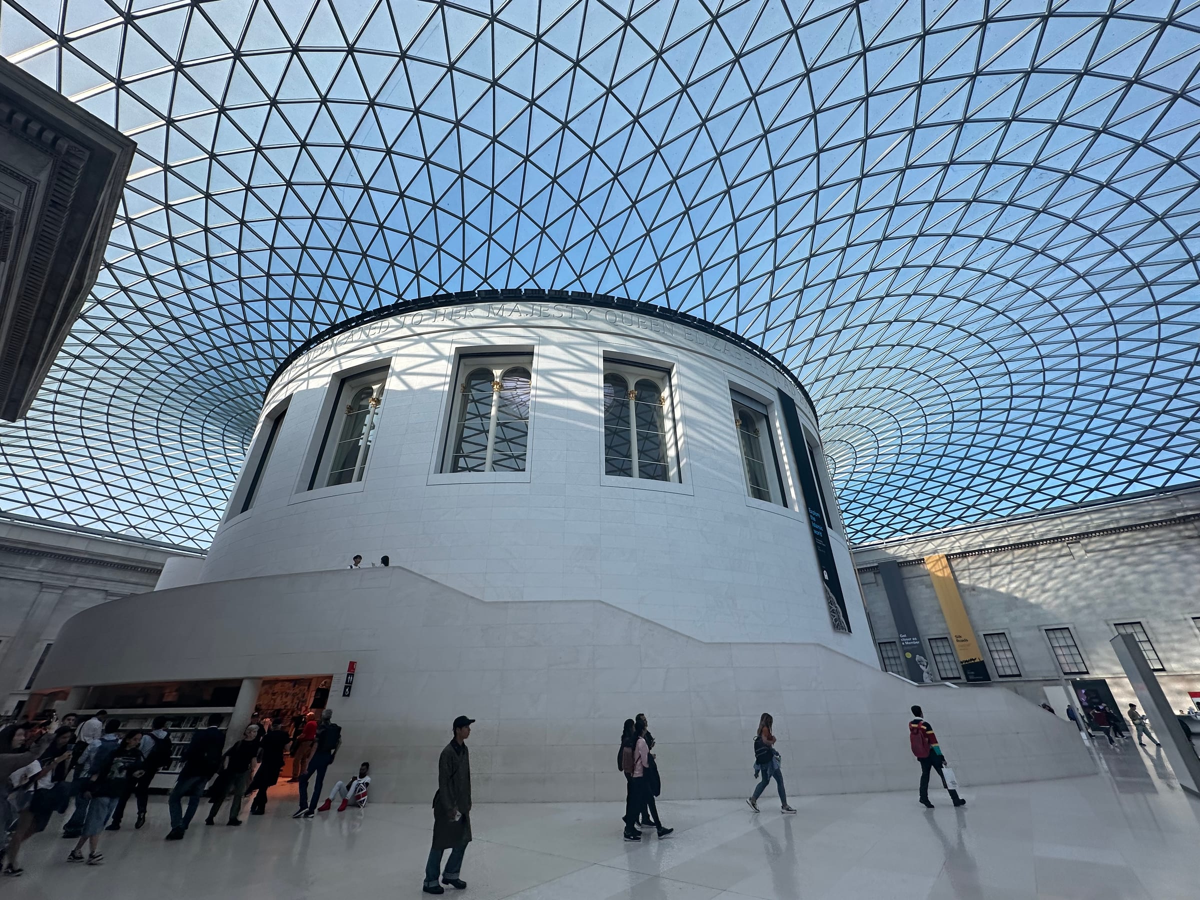 The same glass-roofed courtyard from another angle, light pouring through the geometric canopy onto the floor.