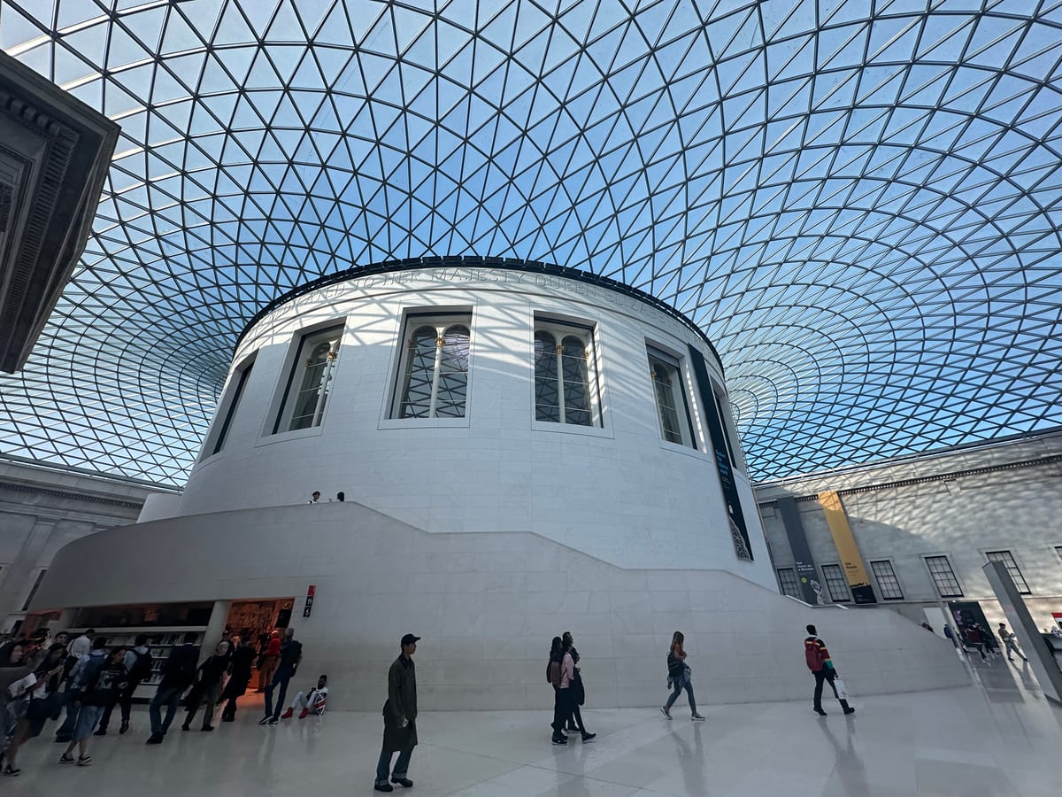 The same glass-roofed courtyard from another angle, light pouring through the geometric canopy onto the floor.
