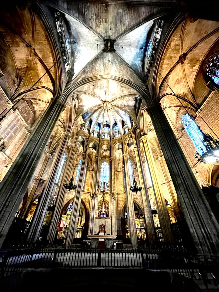 The soaring interior of a Gothic church, slender stone columns rising into a dim vaulted ceiling.