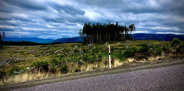 An open road running toward distant hills beneath a sky of dramatic, layered cloud.