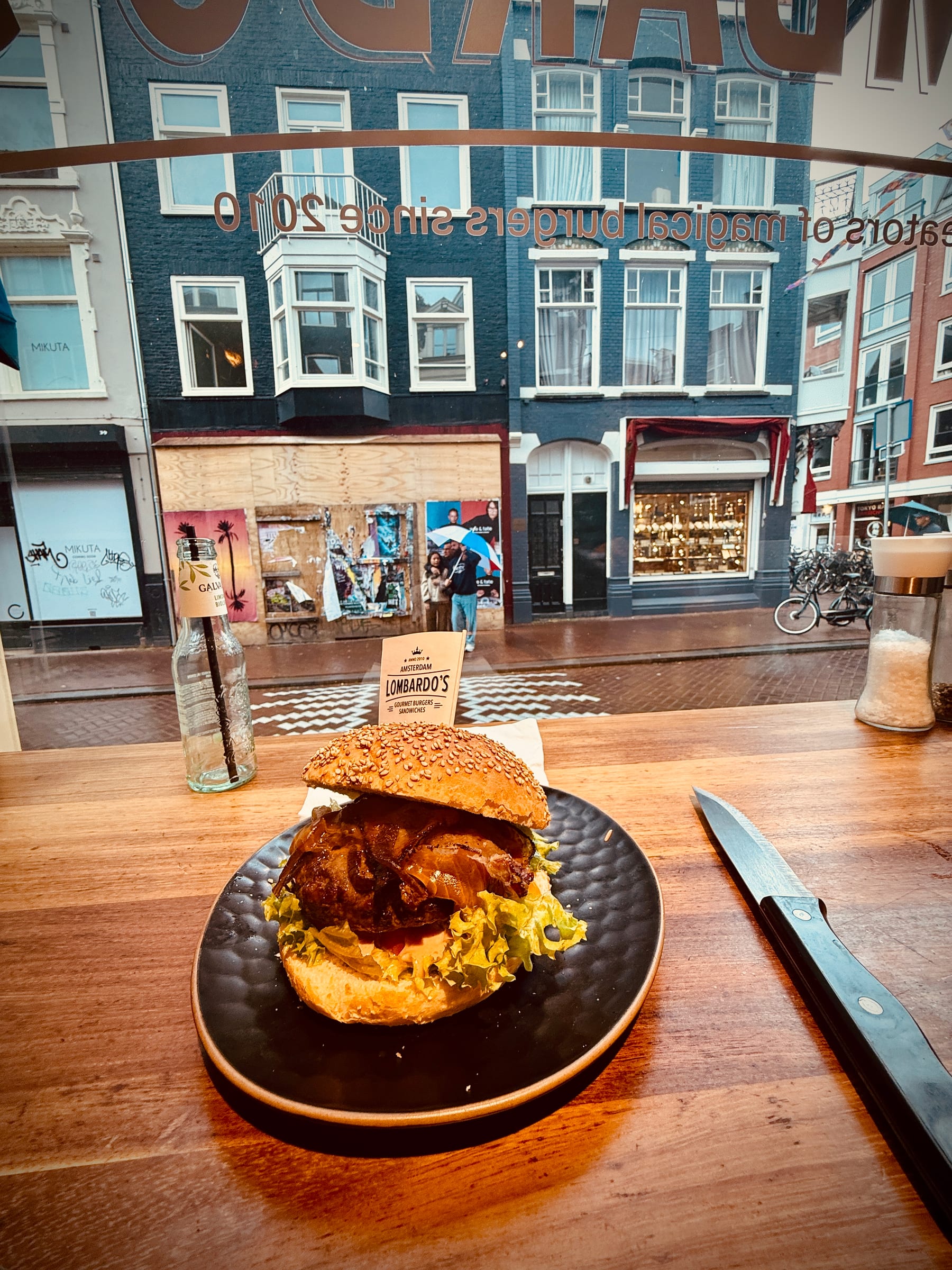 A plated dish on a wooden table beside a window looking out to Amsterdam canal houses.